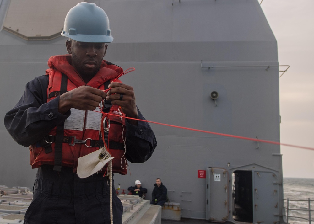 U.S. Navy Counselor 1st Class Demarcus Lancaster, from Houston, ties a knot on the phone and distance line during a replenishment-at-sea