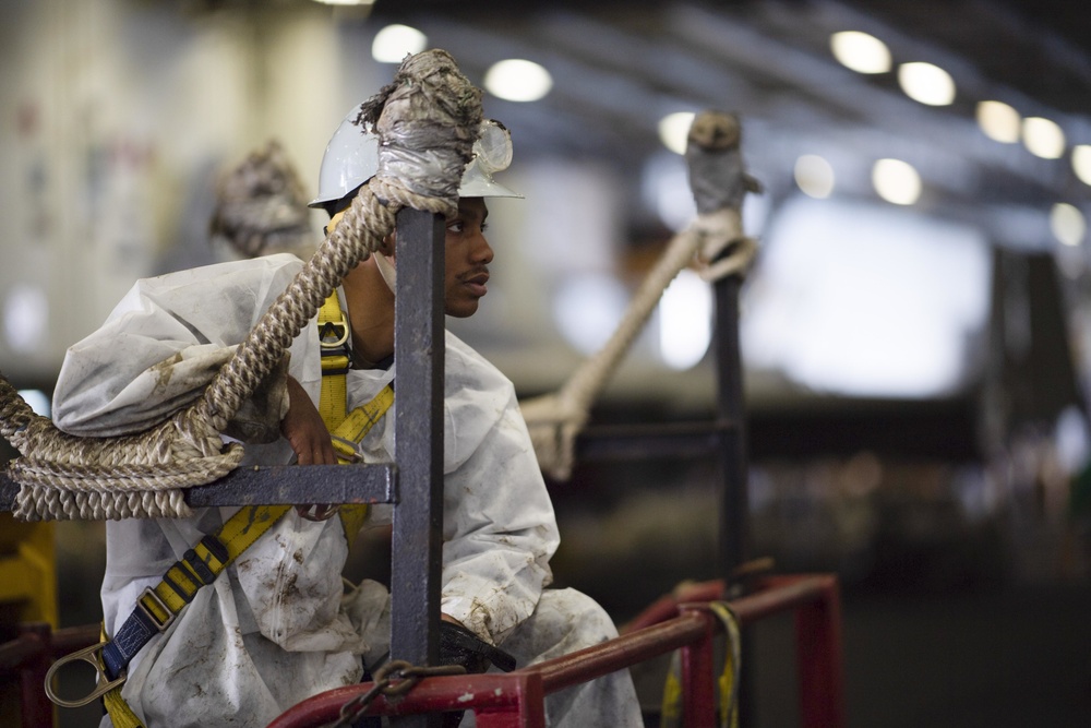 U.S. Sailor prepares to conduct maintenance on a padeye