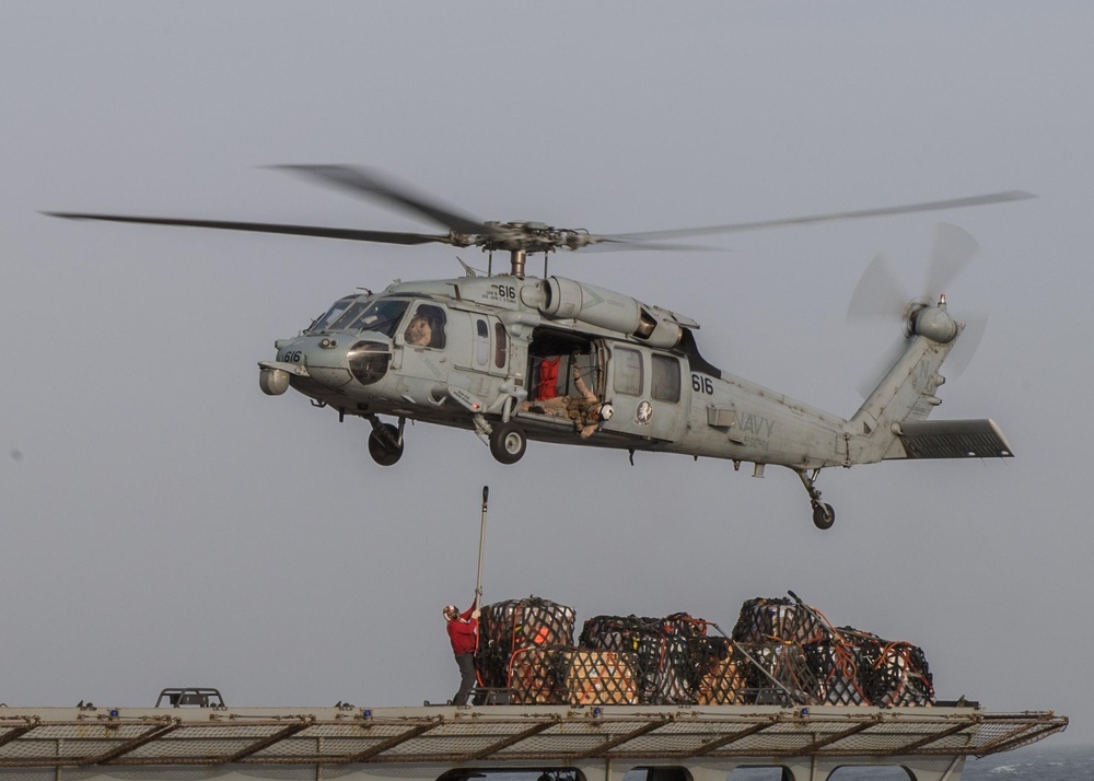 A U.S. Sailor prepares to hook supplies to an MH-60S Sea Hawk, assigned to Helicopter Sea Combat Squadron (HSC) 14