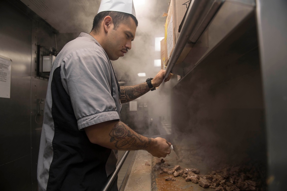 U.S. Navy Culinary Specialist 2nd Class Josue Barajas, from Los Angeles, grills beef in the galley aboard  USS Spruance