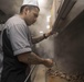 U.S. Navy Culinary Specialist 2nd Class Josue Barajas, from Los Angeles, grills beef in the galley aboard  USS Spruance