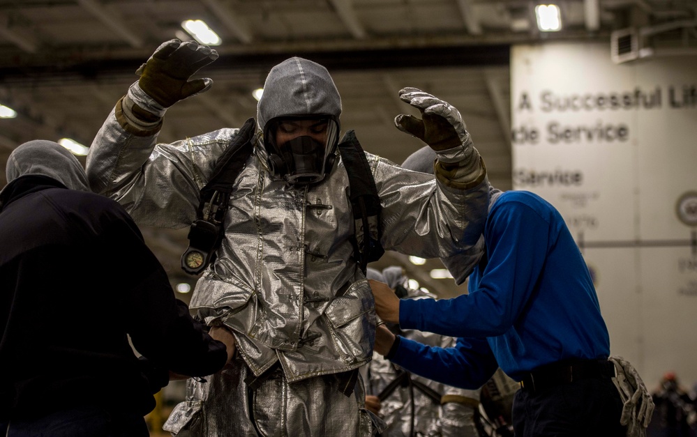 Sailors don firefighting equipment