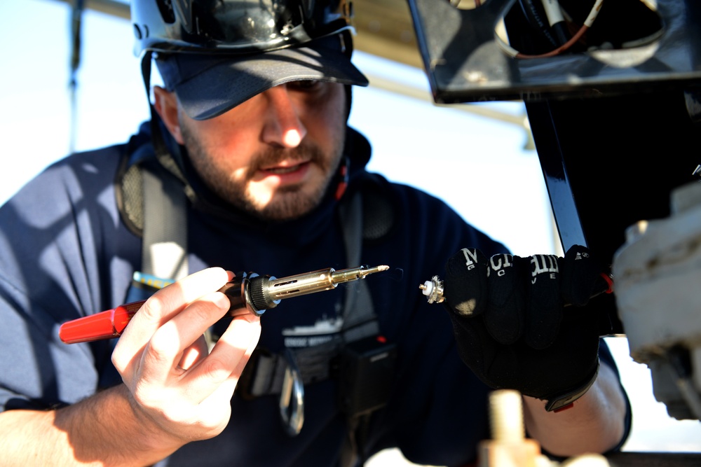 Coast Guard electronics technicians repair critical equipment aboard National Security Cutter while 147’ feet above sea level