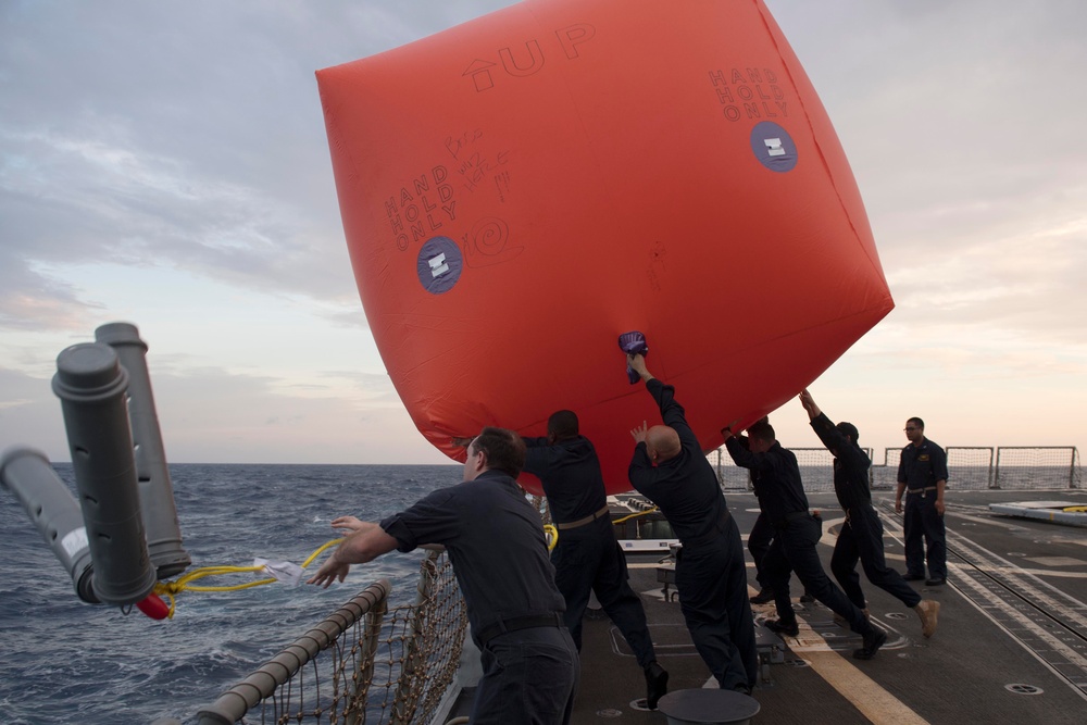 U.S. Sailors deploy an inflatable target from the flight deck of the USS Spruance