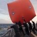 U.S. Sailors deploy an inflatable target from the flight deck of the USS Spruance