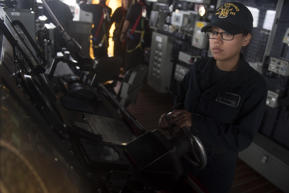 U.S. Navy Seaman Ofelia Velasquez, from West Palm Beach, Florida, stands watch as the helmsman aboard USS Spruance