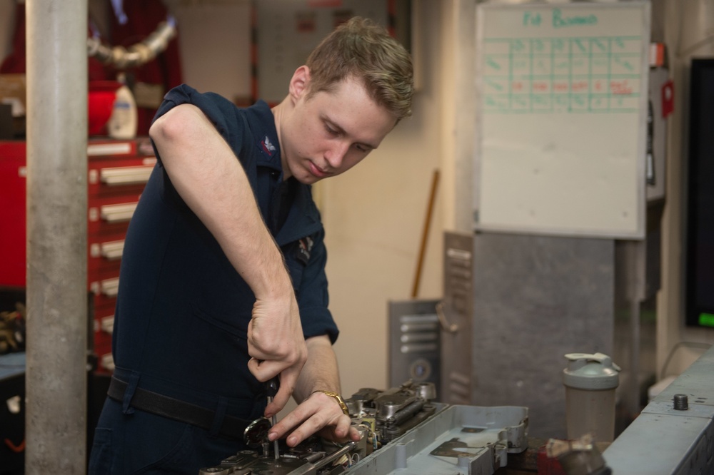 U.S. Sailor  conducts maintenance on a bomb rack unit