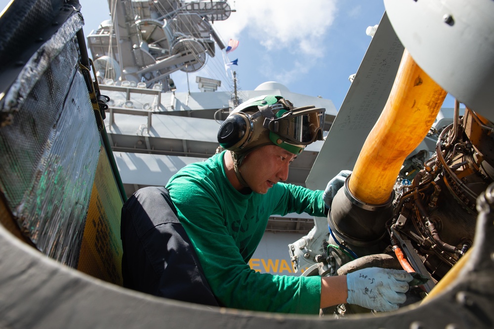 U.S. Sailor cleans mechanics on an MH-60S Sea Hawk