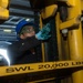 U.S. Sailor greases a lift chain on a forklift