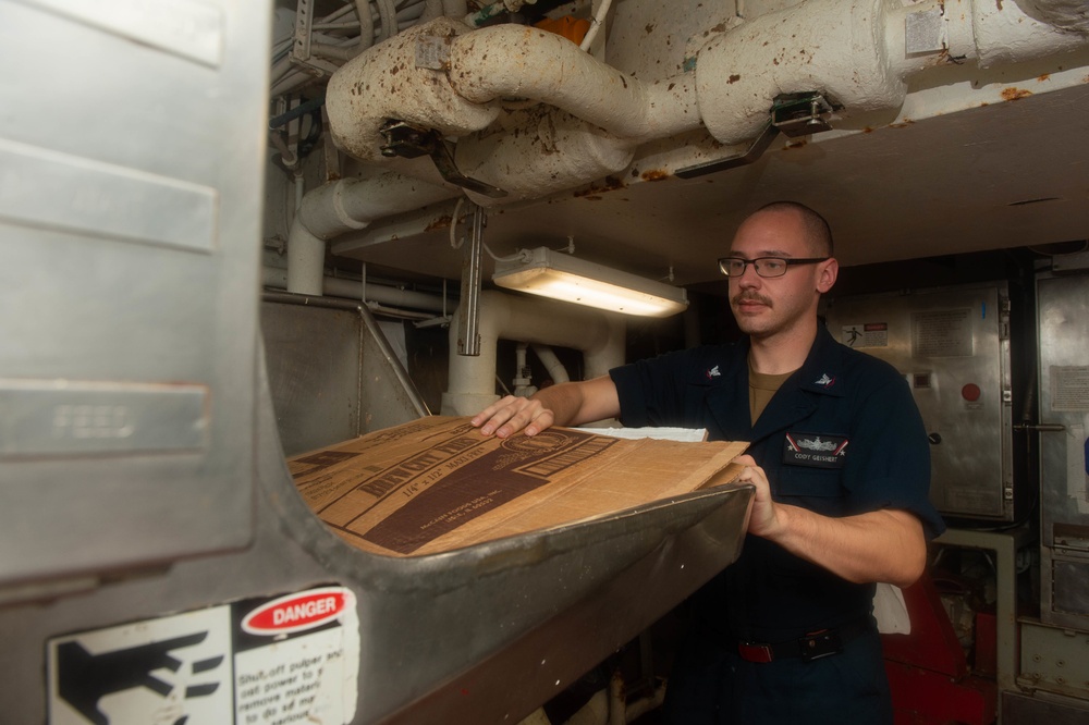 U.S. Sailor places cardboard into a pulper