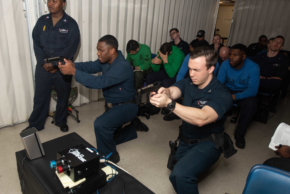 U.S. Sailors trains with an M9 pistol fitted for a Multiple Interactive Learning/Training Objectives Range