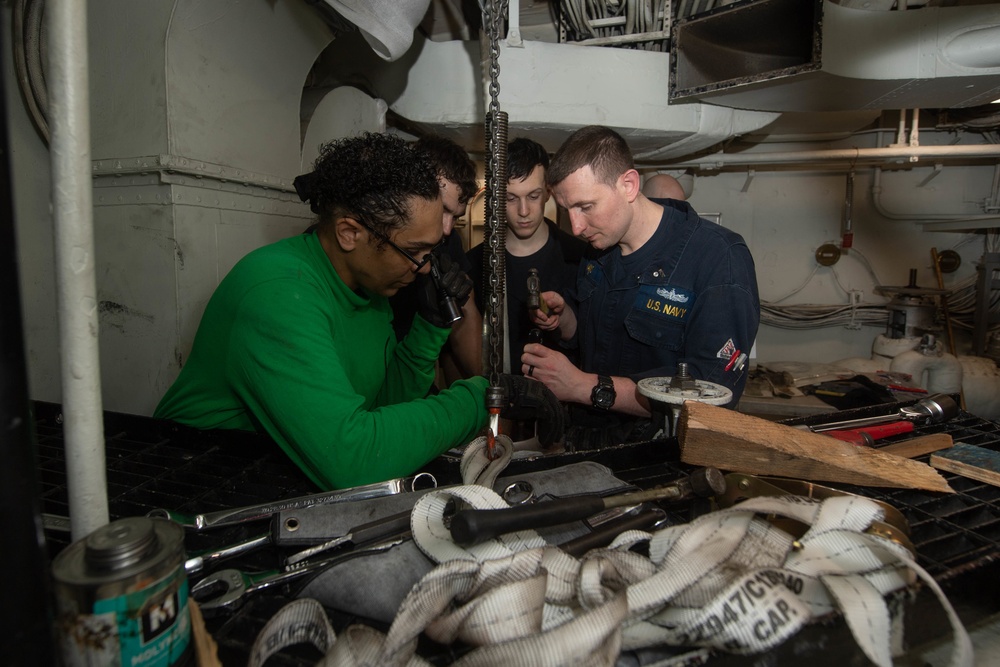 U.S. Sailors replace a silver seal on a cross-connect valve for a steam-powered catapult