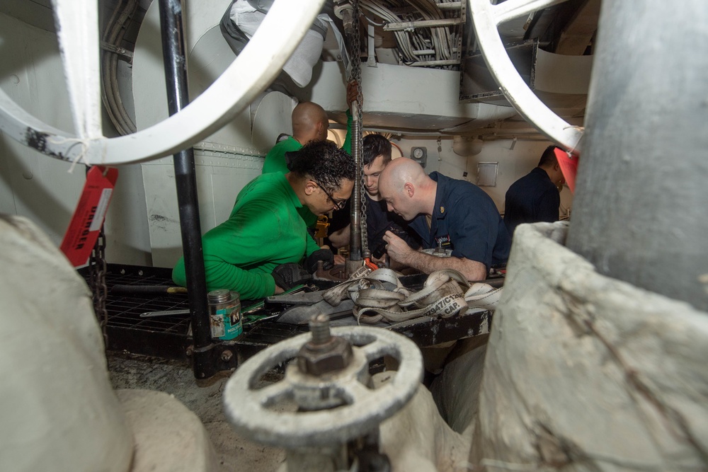 U.S. Sailors replace a silver seal on a cross-connect valve for a steam-powered catapult