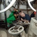 U.S. Sailors replace a silver seal on a cross-connect valve for a steam-powered catapult