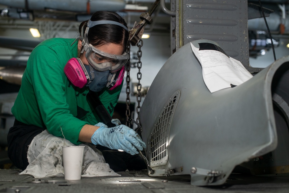 U.S. Sailor paints a cowling for an MH-60S Sea Hawk