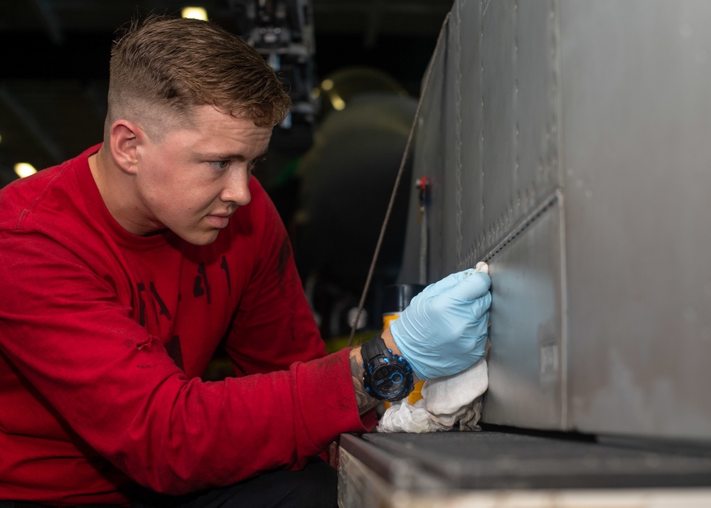 U.S. Sailor conducts corrosion prevention on an F/A-18F Super Hornet