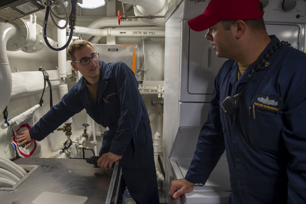 U.S. Navy Boatswain’s Mate Chief Christopher Haws explains ways to plug a simulated hole in the bulk head