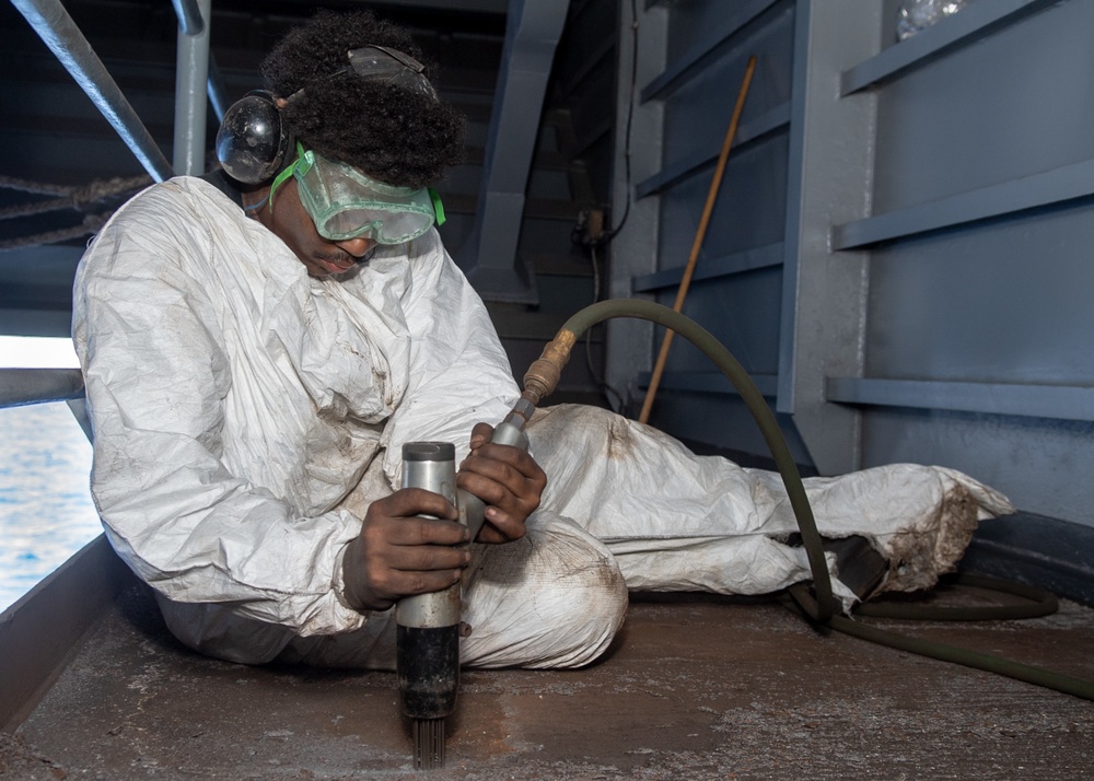 U.S. Sailor conducts deck preservation with a needle gun