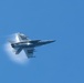 An F/A-18E Super Hornet flies over the aircraft carrier USS John C. Stennis (CVN 74)