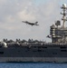 An F/A-18E Super Hornet flies over the flight deck of the aircraft carrier USS John C. Stennis (CVN 74)
