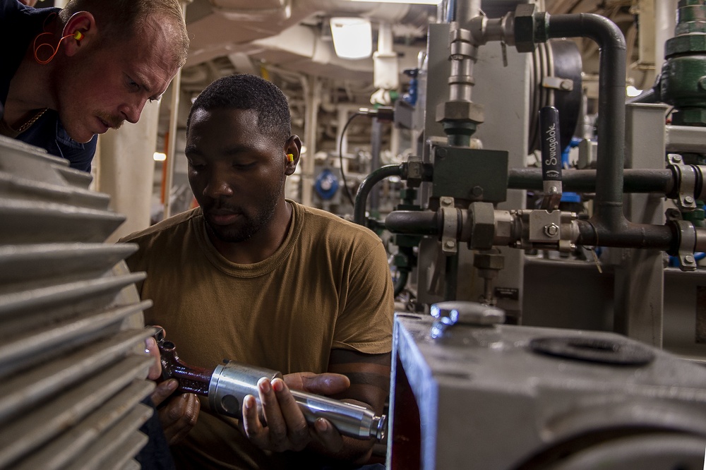 U.S. Navy Engineman 1st Class Blake Petenbrink, from St. Marys, Ga., and Machinist’s Mate 3rd Class Christopher Johnson, from Mt. Vernon, N.Y., inspect a piston prior to installing it in a drive end assembly of a high-pressure pump aboard the Arleigh Bur
