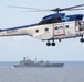 An SA-330J Puma helicopter flies alongside the guided-missile cruiser USS Mobile Bay (CG 53)