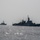 Two naval warships are operating in open sea under overcast, hazy conditions. The foreground vessel is clearly marked 'F946' and displays what appears to be a flag on its mast, while a second warship is visible in the background to the left. Both vessels appear to be underway in calm-to-moderate seas.