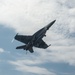 An F/A-18E Super Hornet flies over the flight deck of the aircraft carrier USS John C. Stennis (CVN 74)