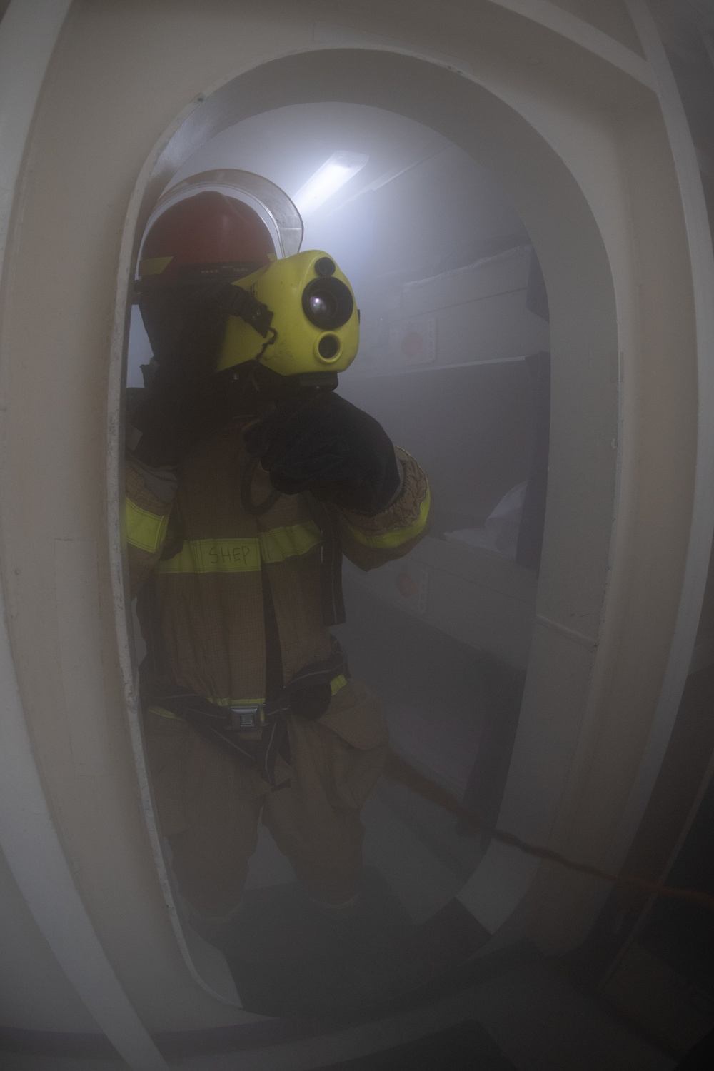 U.S. Sailor checks for hot spots with a Naval Firefighting Thermal Imager during a simulated fire