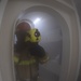 U.S. Sailor checks for hot spots with a Naval Firefighting Thermal Imager during a simulated fire