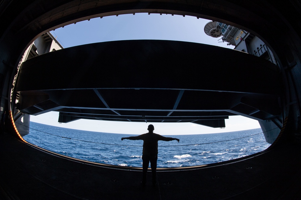 U.S. Sailor signals to lower an aircraft elevator