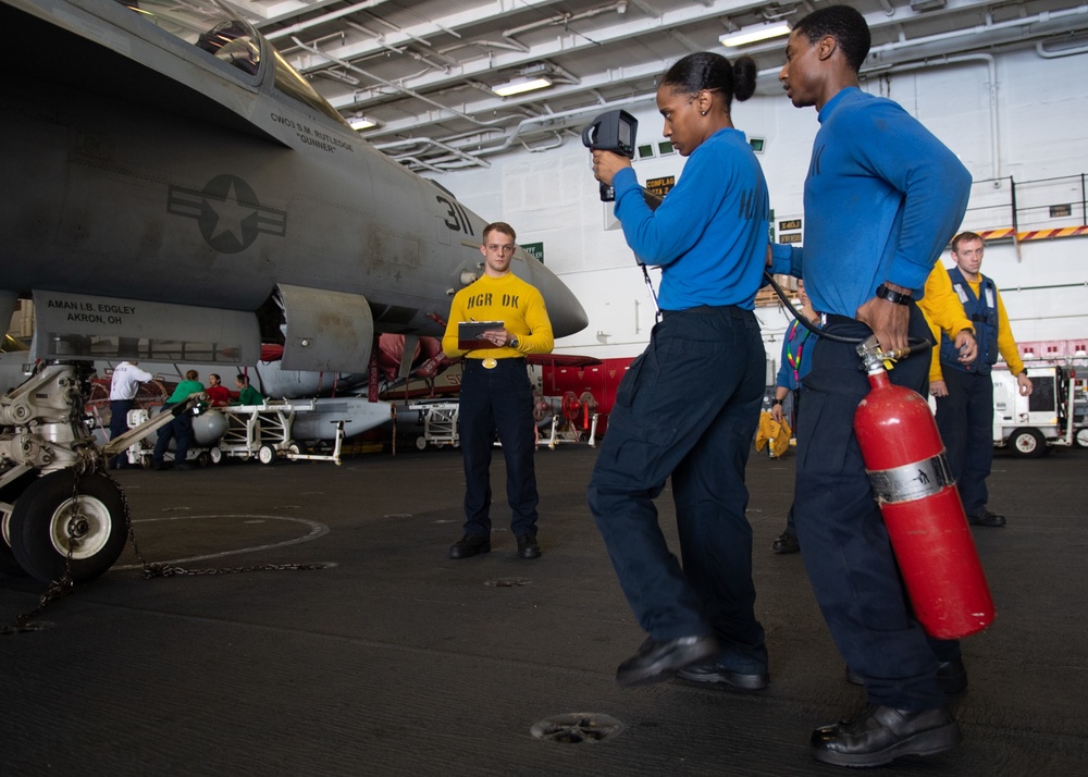 U.S. Sailors simulate overhauling a fire on an F/A-18E Super Hornet