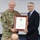 A U.S. Army Captain named Campbell, wearing OCP (Operational Camouflage Pattern) uniform, is being presented with a framed 'State of Texas Citation' by a civilian man in a dark suit. The ceremony appears to be an award presentation, likely taking place in a military or government facility. Both individuals are smiling and jointly holding the framed document for the photo.