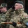 20th anniversary of NATO expansion Two military officers are shown saluting during what appears to be a formal ceremony. The foreground officer wears a green beret and Hungarian military uniform with visible name tape 'ASZTALOS' and country identifier 'HUNGARY', along with a European Union/EUFOR patch. A second officer in a different camouflage pattern salutes in the background.