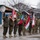 20th anniversary of NATO expansion A military ceremony featuring soldiers from multiple nations standing in formation during winter conditions. Soldiers are holding national flags including those of Poland, Czech Republic, and Hungary, suggesting a multinational military event or parade. The scene appears to take place at a military base or installation, with snow visible on rooftops and trees in the background.