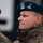 20th anniversary of NATO expansion A military officer wearing a teal/dark green beret with a Polish Army eagle badge and two-star rank insignia is shown in profile view. He is dressed in Polish woodland camouflage (wz. 93 pattern) uniform. A second soldier wearing a similar beret is partially visible in the background.
