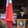 20th anniversary of NATO expansion A civilian official is delivering a speech at a podium during a formal military ceremony for the Polish Military Contingent EUFOR ALTHER (XVI rotation). The setting includes NATO and Polish national flags, with military personnel visible in the foreground. The event appears to be an official handover or deployment ceremony.