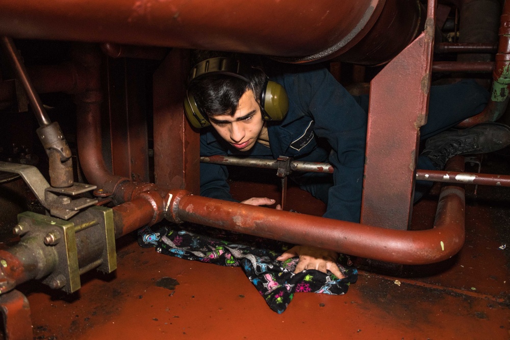 Sailor Cleans Bilge in Engineering Space Aboard USS Harpers Ferry (LSD 49).