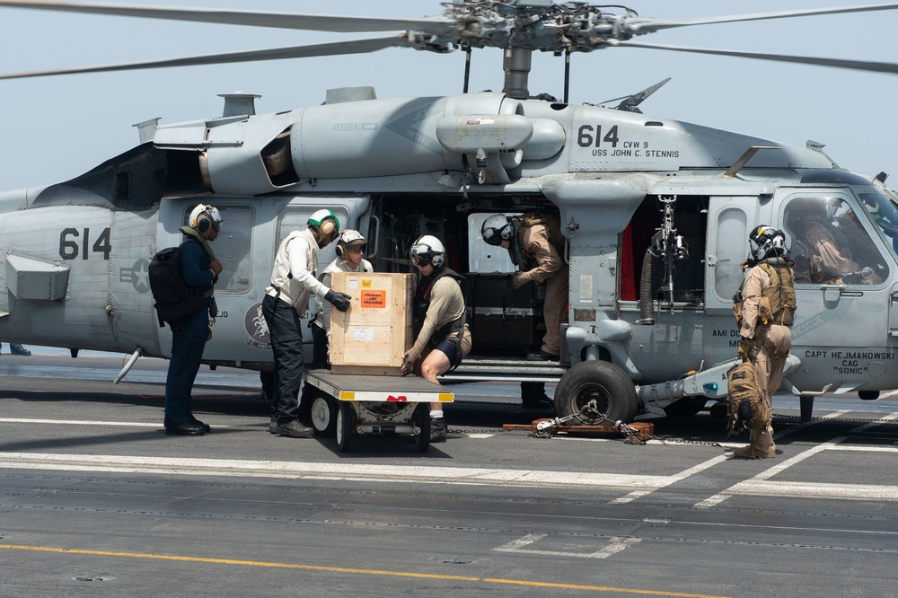 U.S. Sailors load cargo into an MH-60S Sea Hawk