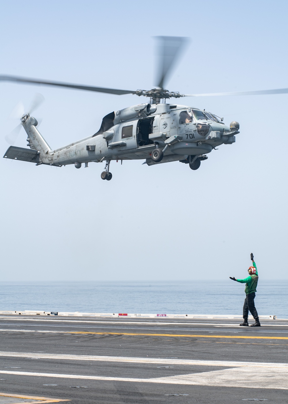 U.S. Sailor signals an MH-60R Sea Hawk assigned to Helicopter Maritime Strike Squadron (HSM) 71