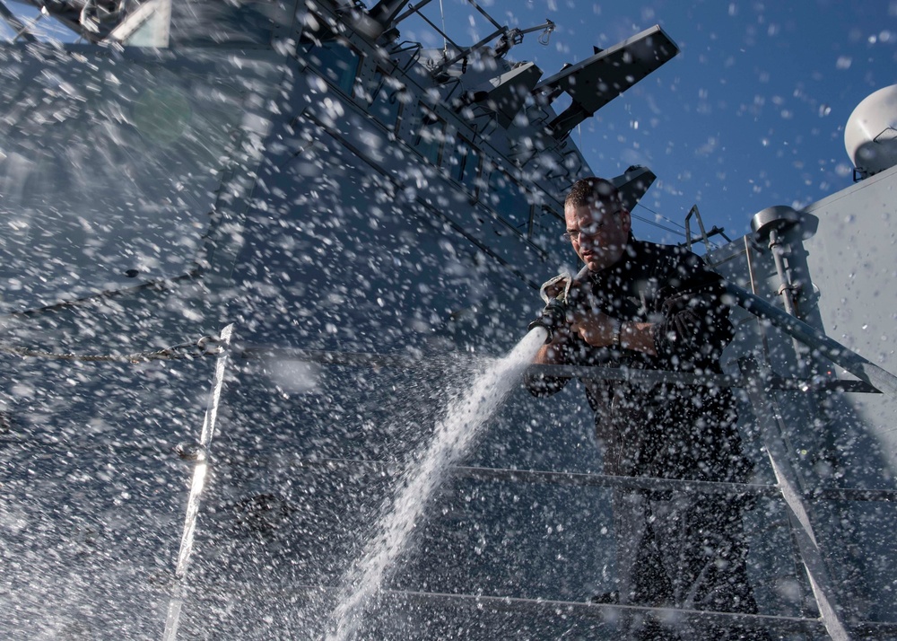 Sailor hoses down the exterior of the USS Carney (DDG 64)