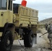 Soldier sprays water to decontaminate truck