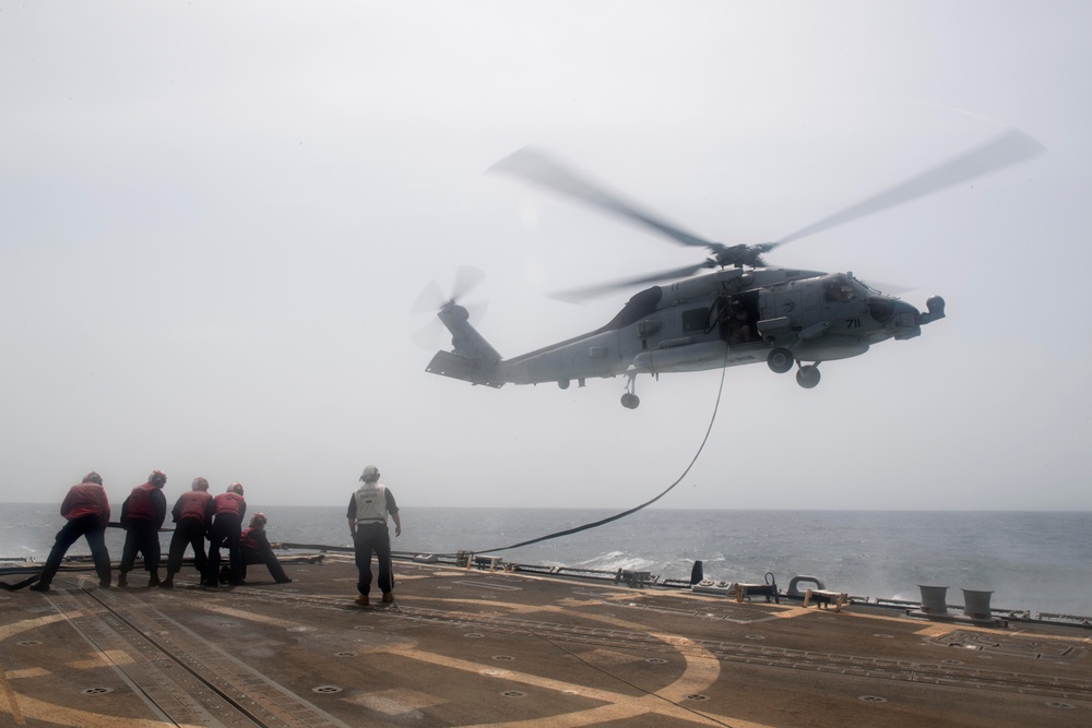 U.S. Sailors perform an inflight refueling with an MH-60R Sea Hawk on the flight deck of  USS Spruance