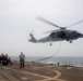 U.S. Sailors perform an inflight refueling with an MH-60R Sea Hawk on the flight deck of  USS Spruance