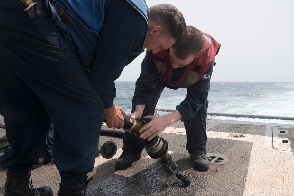 U.S. Sailors rig a fuel line aboard the flight deck of USS Spruance