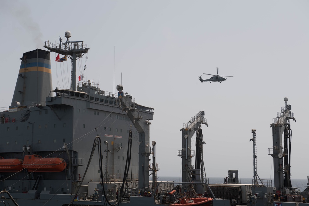 An MH-60R Sea Hawk flies near the fleet replenishment oiler USNS Kanawha