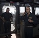 Commodore of Destroyer Squadron 21 uses the 1 main circuit (1MC) to address the crew aboard USS Spruance