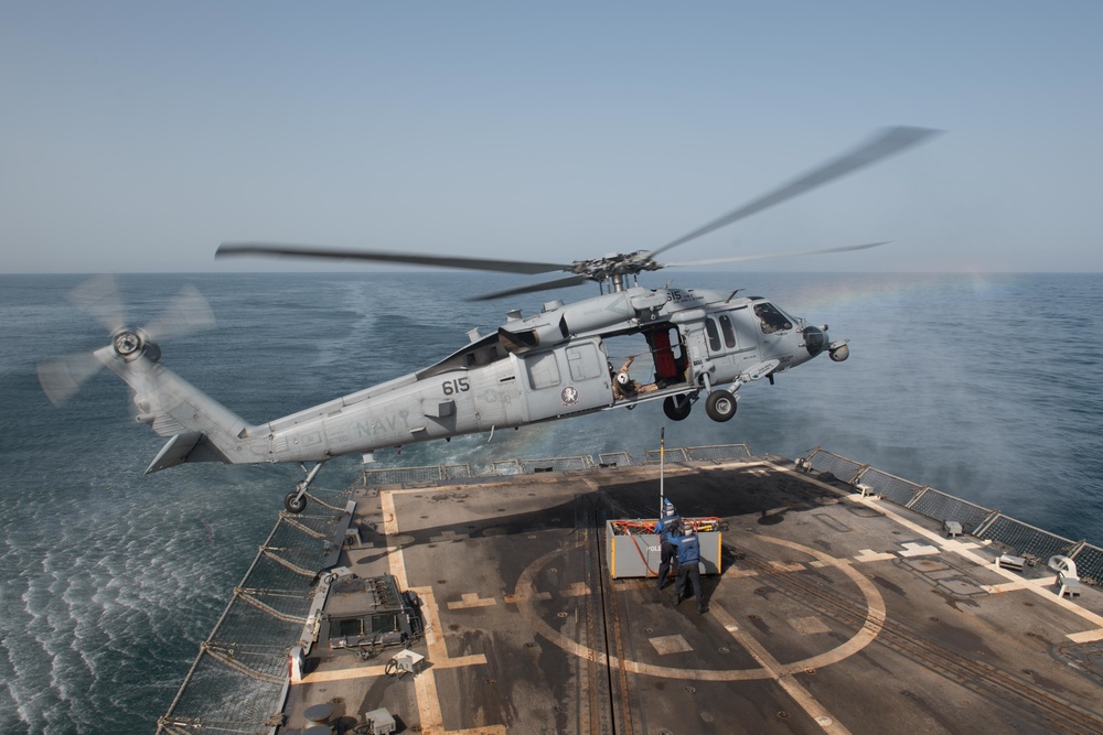 Sailors return to the safety line after attaching cargo to an MH-60S Sea Hawk