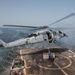 Sailors return to the safety line after attaching cargo to an MH-60S Sea Hawk