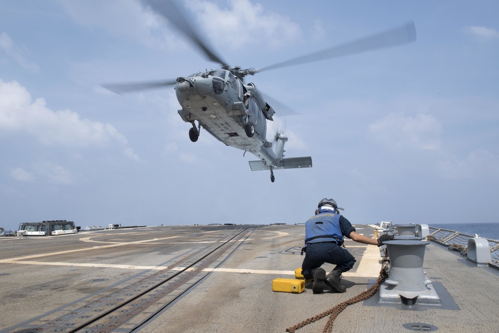 U.S. Navy Boatswain’s Mate prepares to chock and chain an MH-60S Sea Hawk